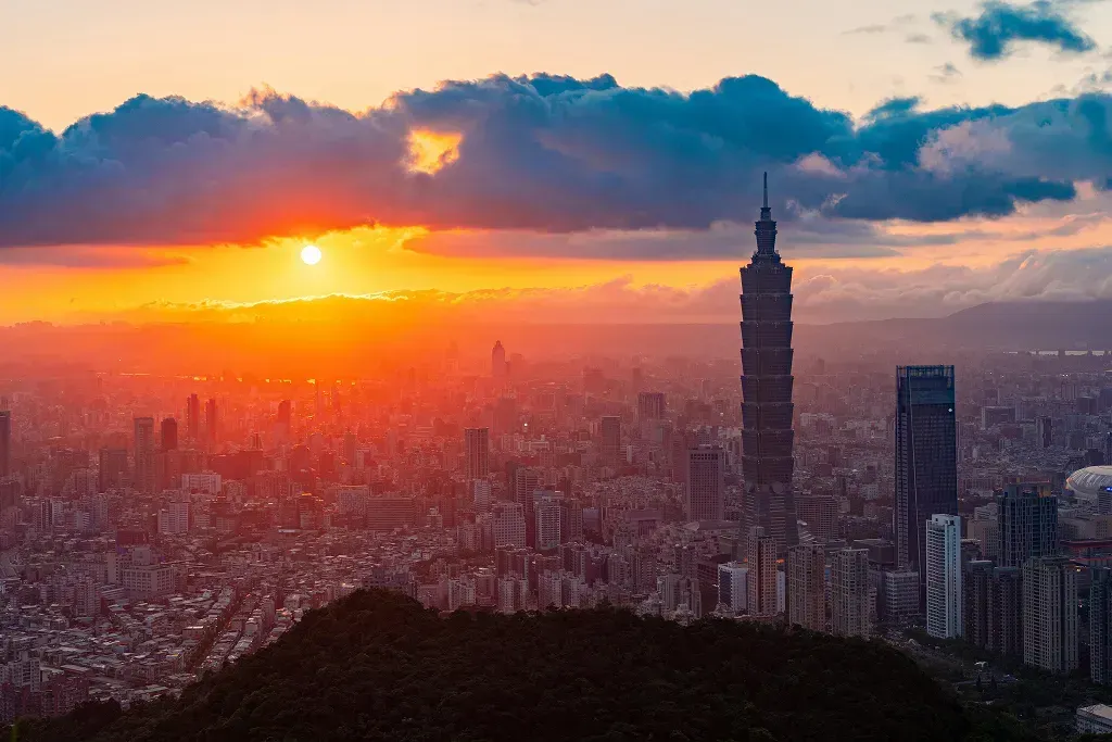 Sonce zahaja nad mestom, ki ga krasu znameniti nebotičnik Taipei 101.